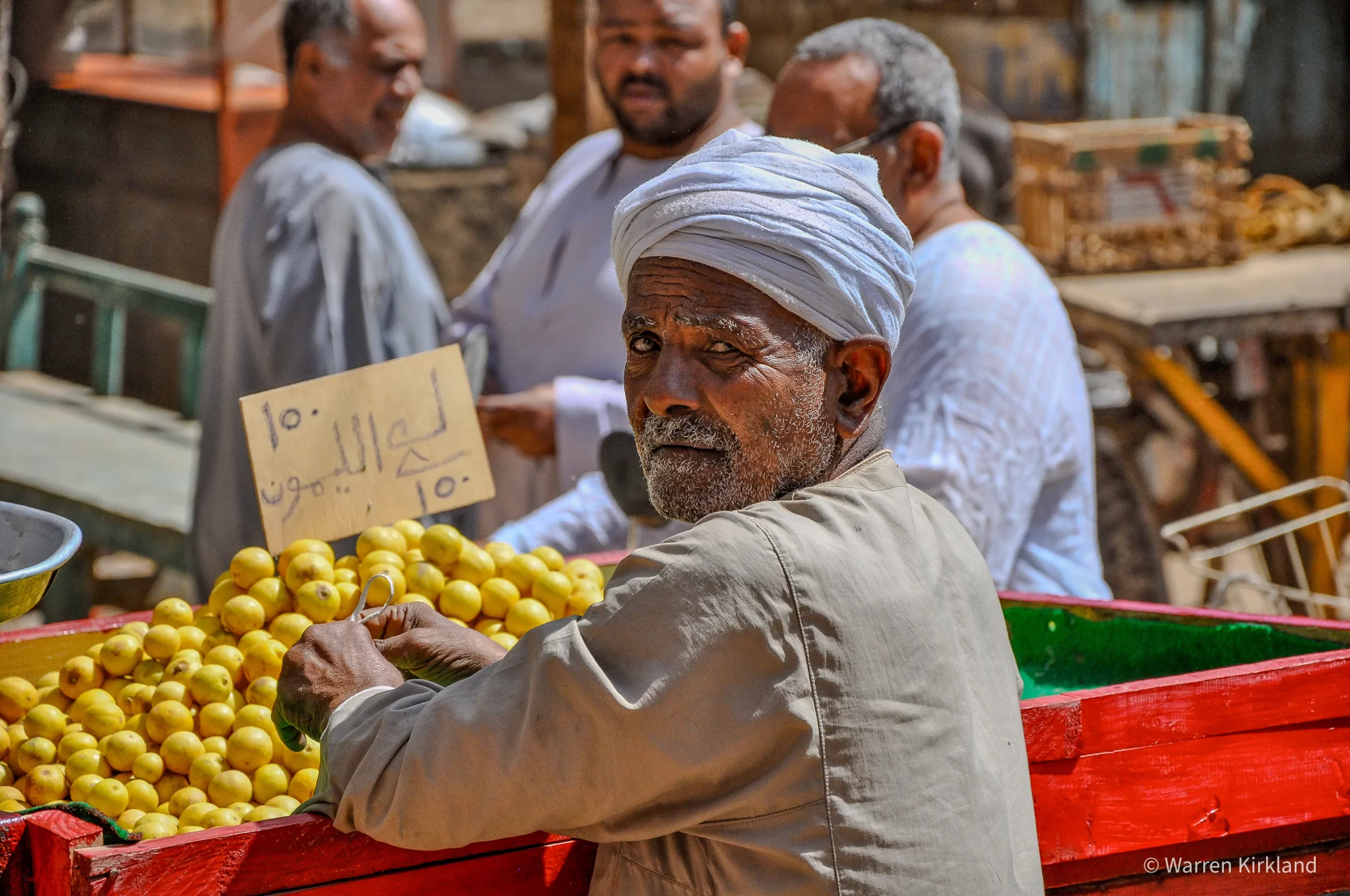 Fruit seller glancing at the camera beside his market cart, Egypt
