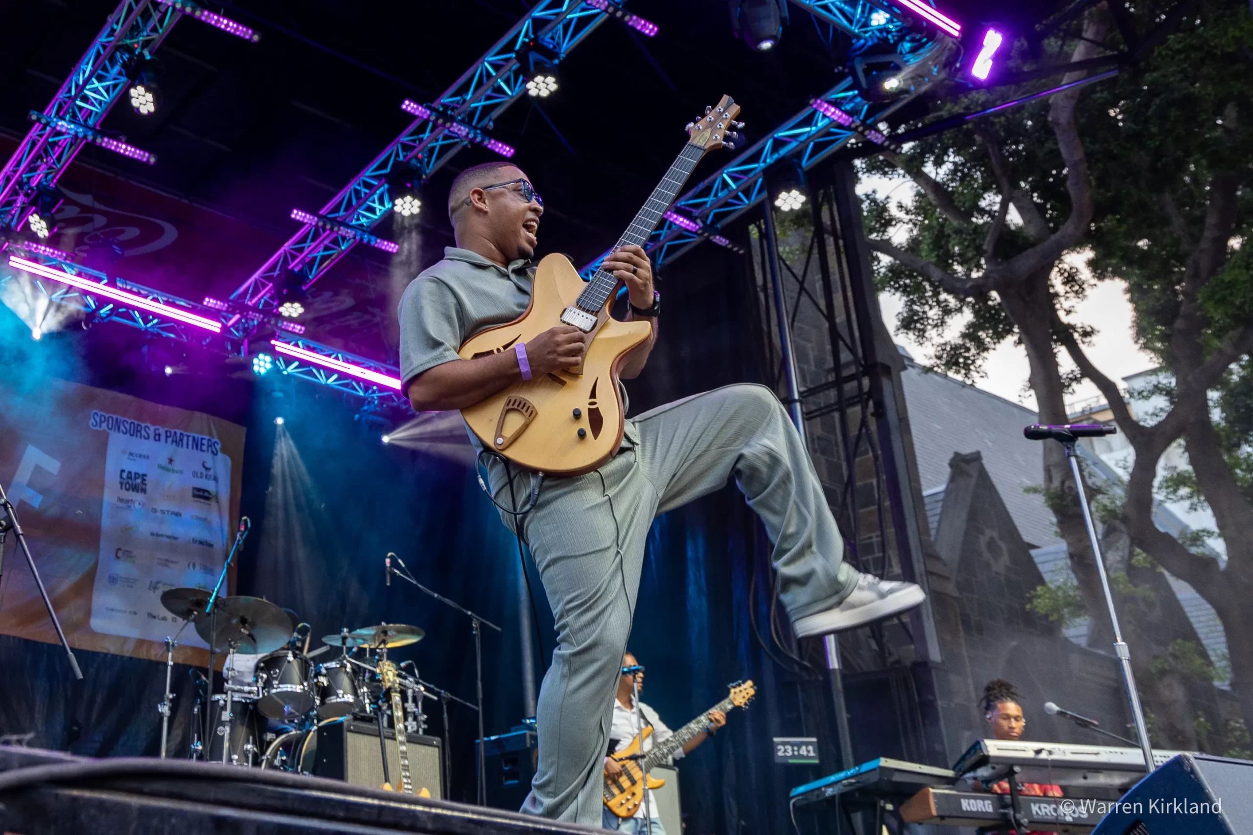 Cameron Ward playing electric guitar mid-jump on stage