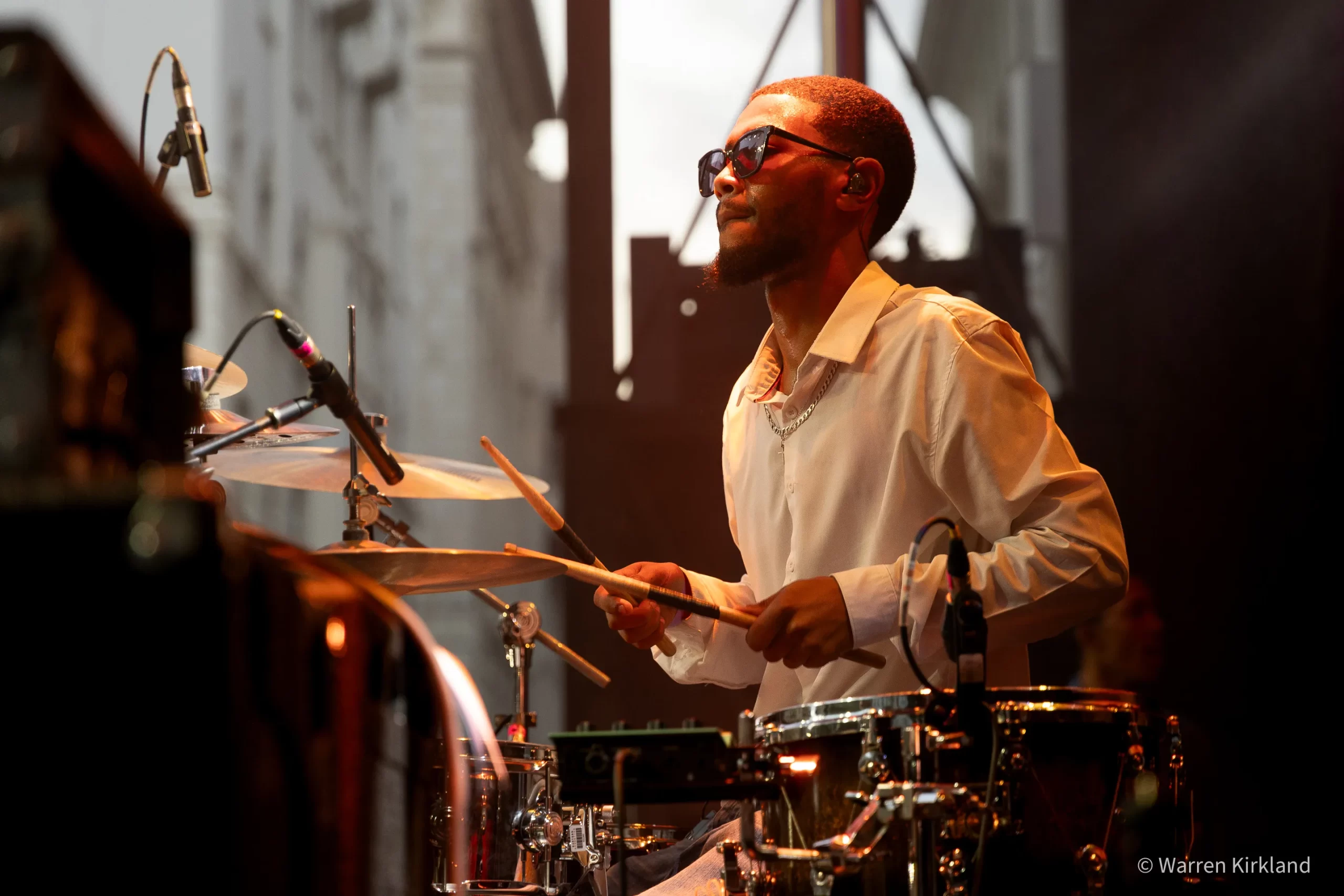 Cameron Ward playing drums under warm stage lighting