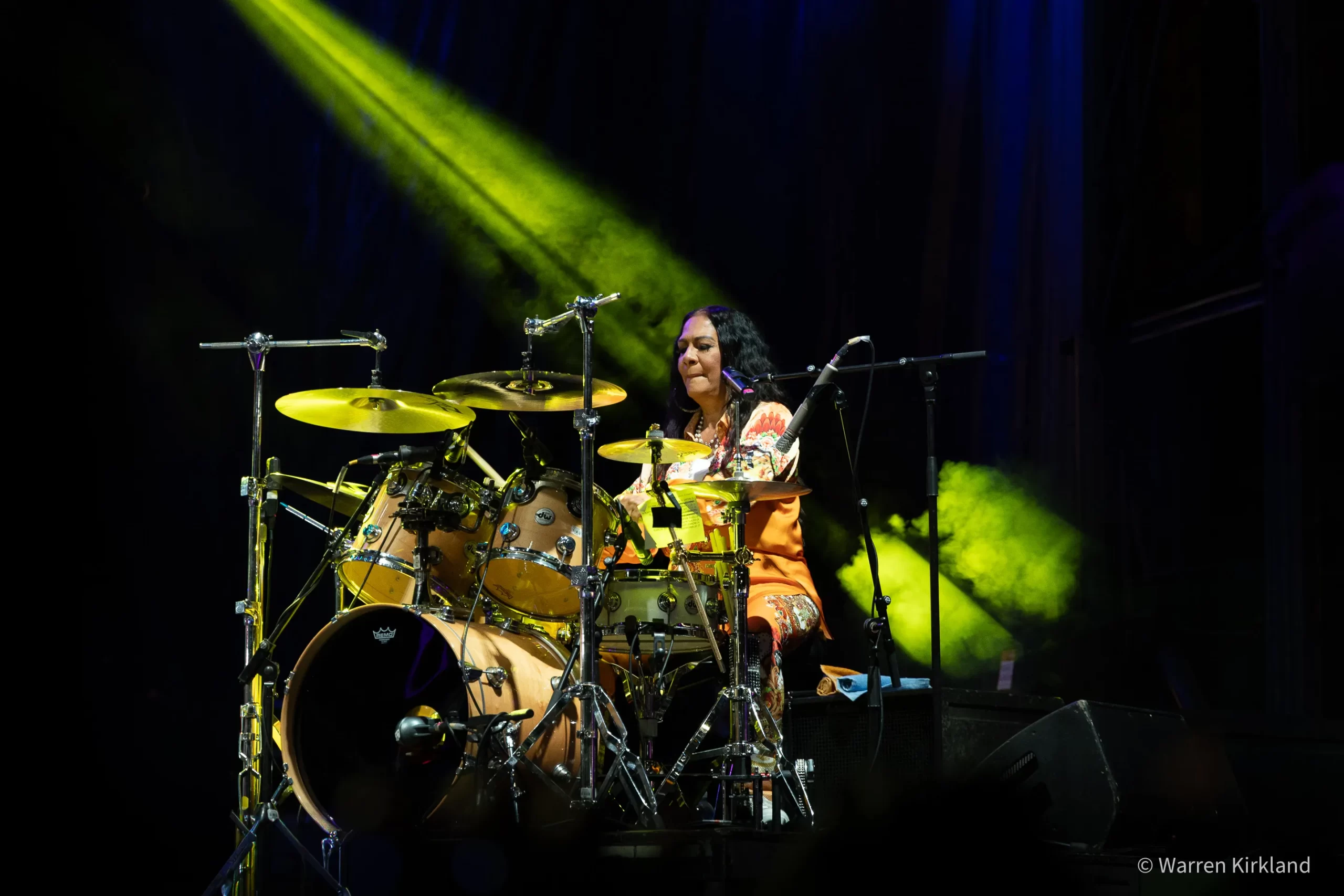 Sheila E. drumming with The E-Train under green light beams
