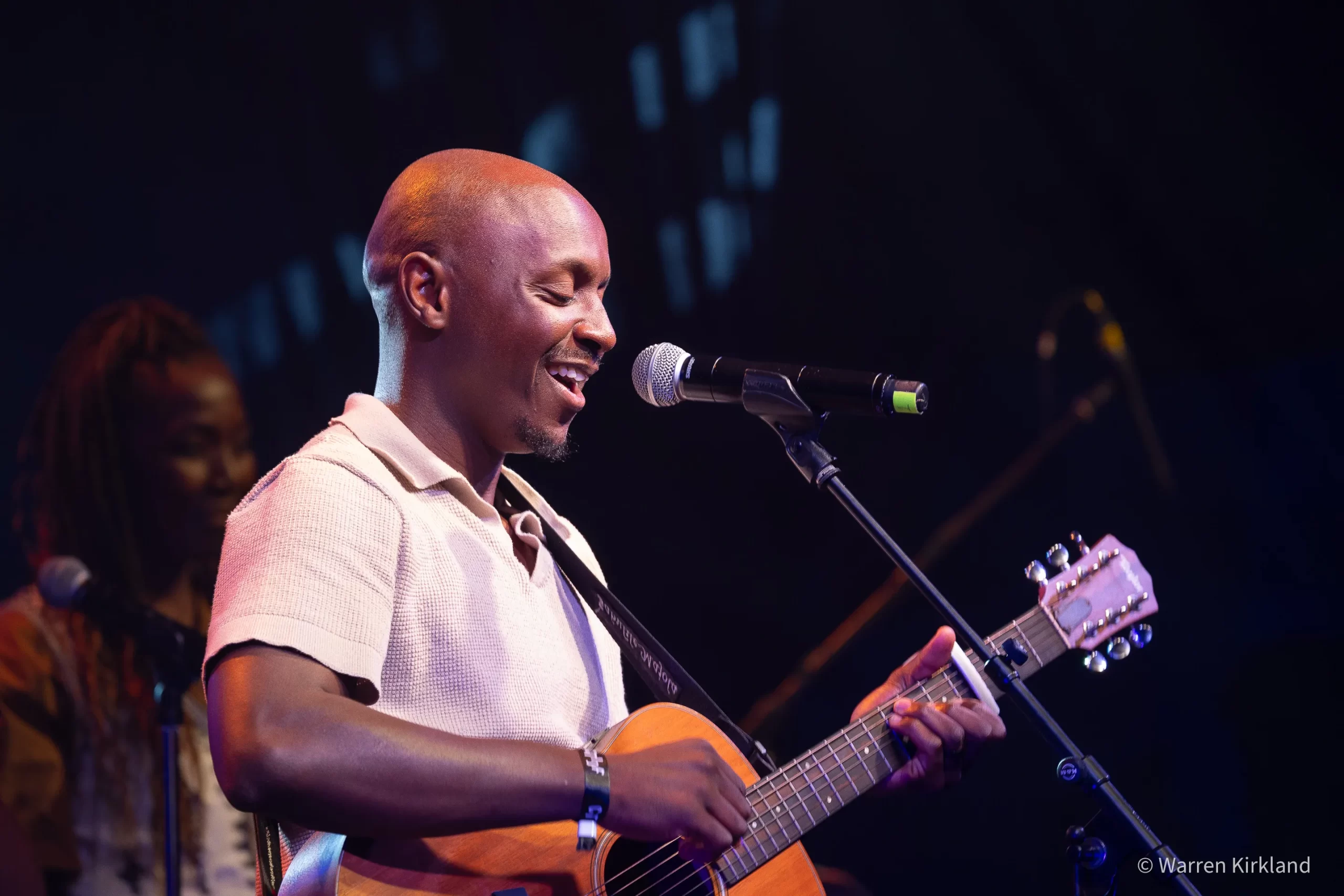 Jabulile Majola singing and playing acoustic guitar on stage