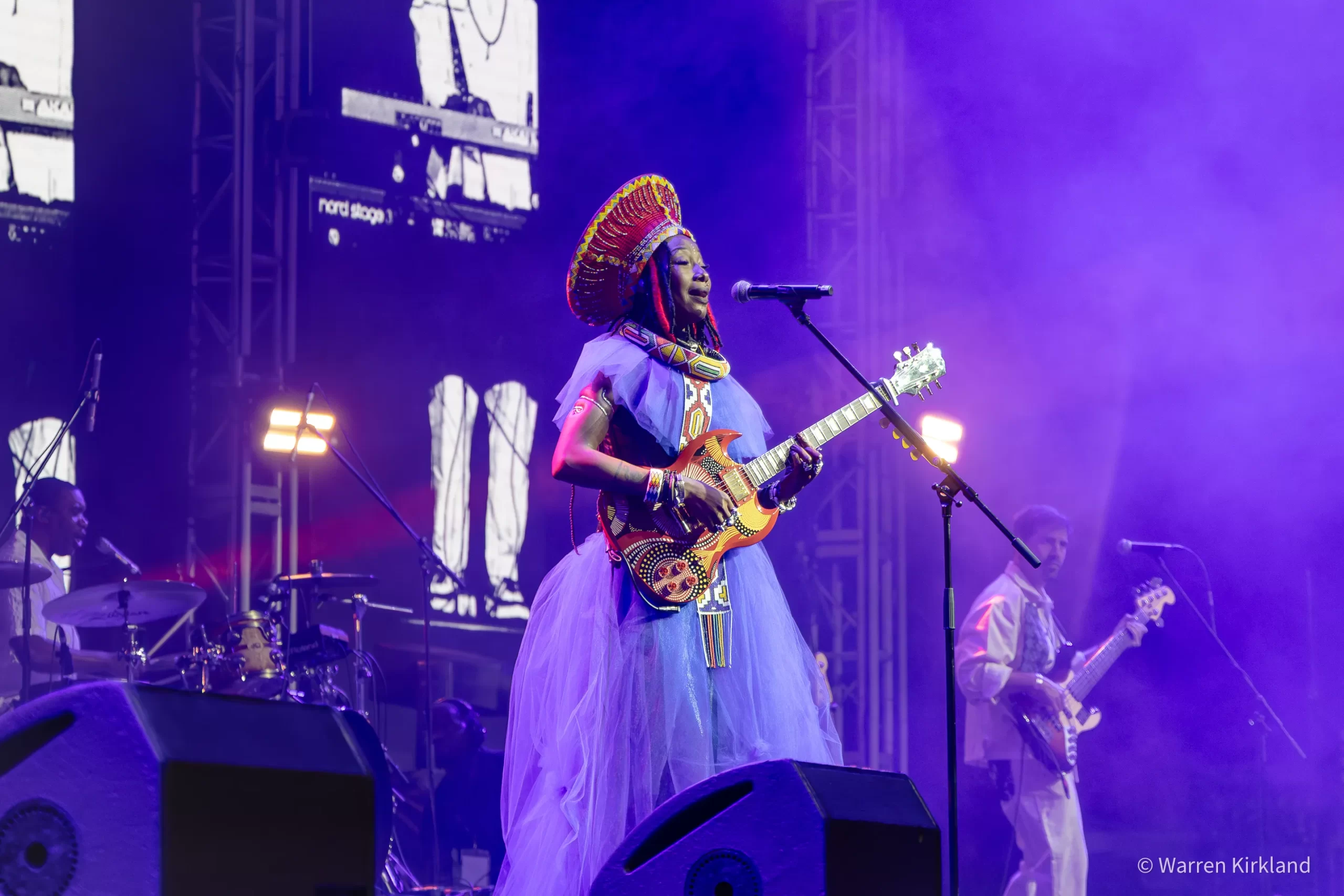 Fatoumata Diawara playing electric guitar on stage under purple lights