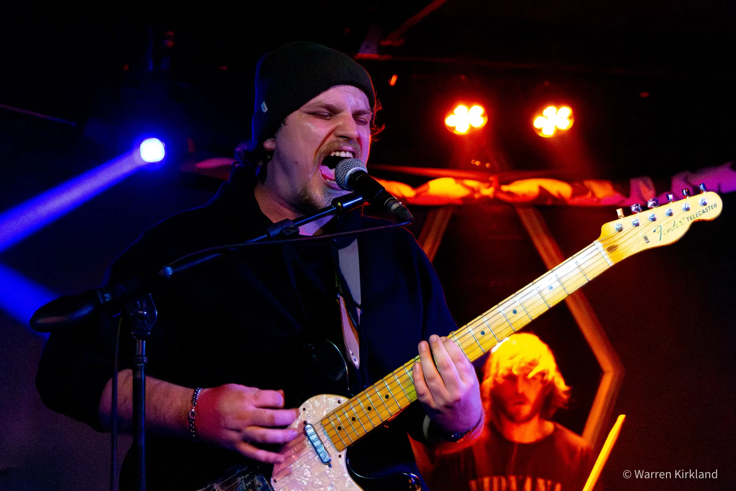 Hi Anxious guitarist singing into the microphone under blue and red lights