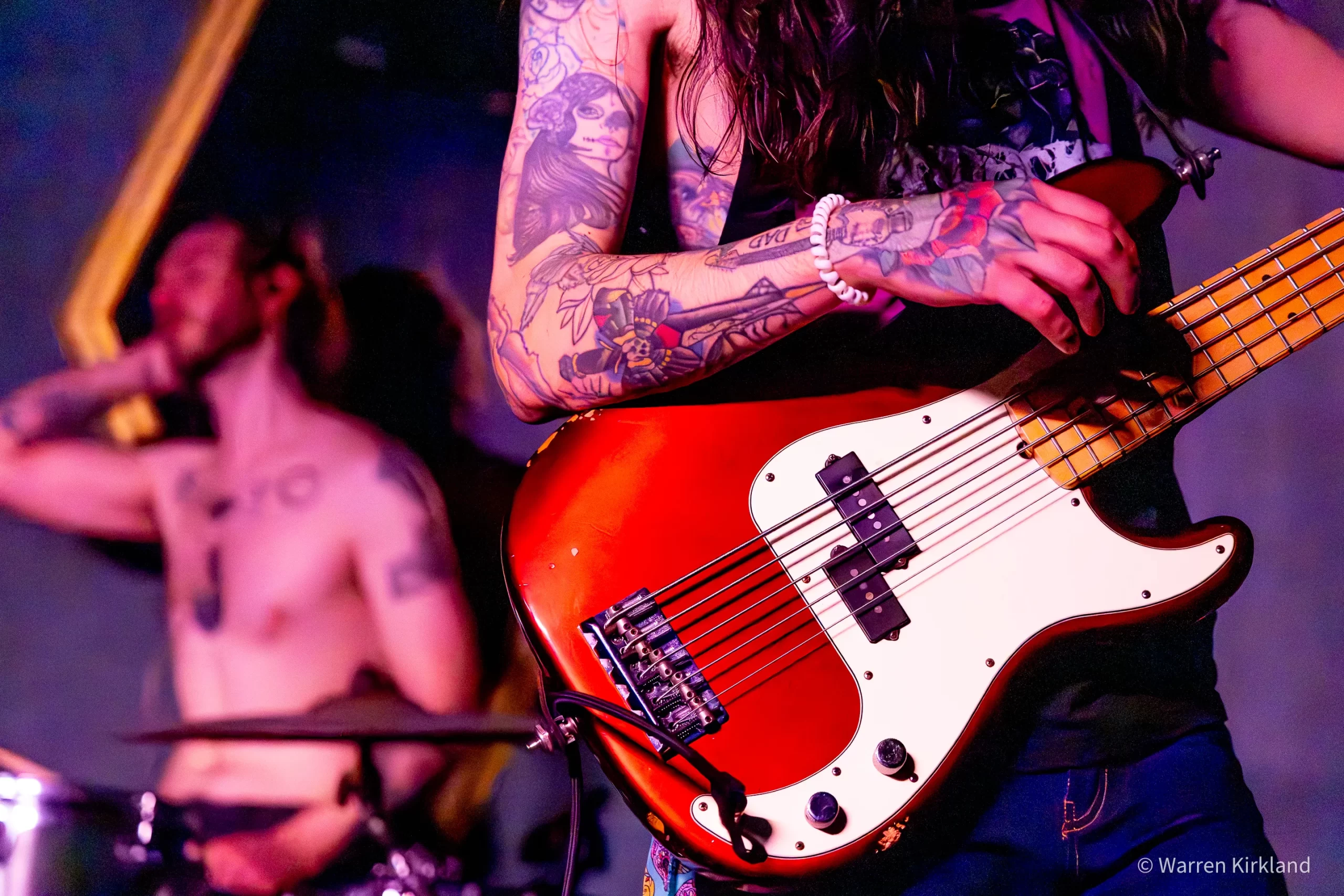 Close-up of a Hi Anxious member playing a red bass guitar
