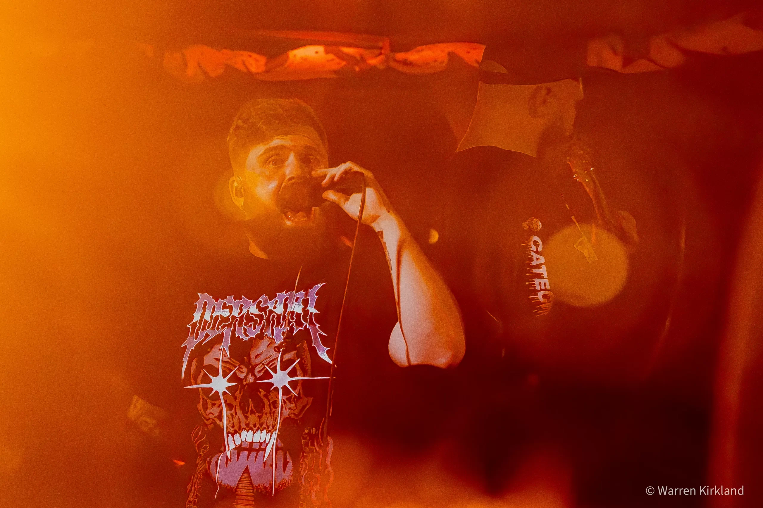 The Talon vocalist screaming into a microphone under intense orange lighting