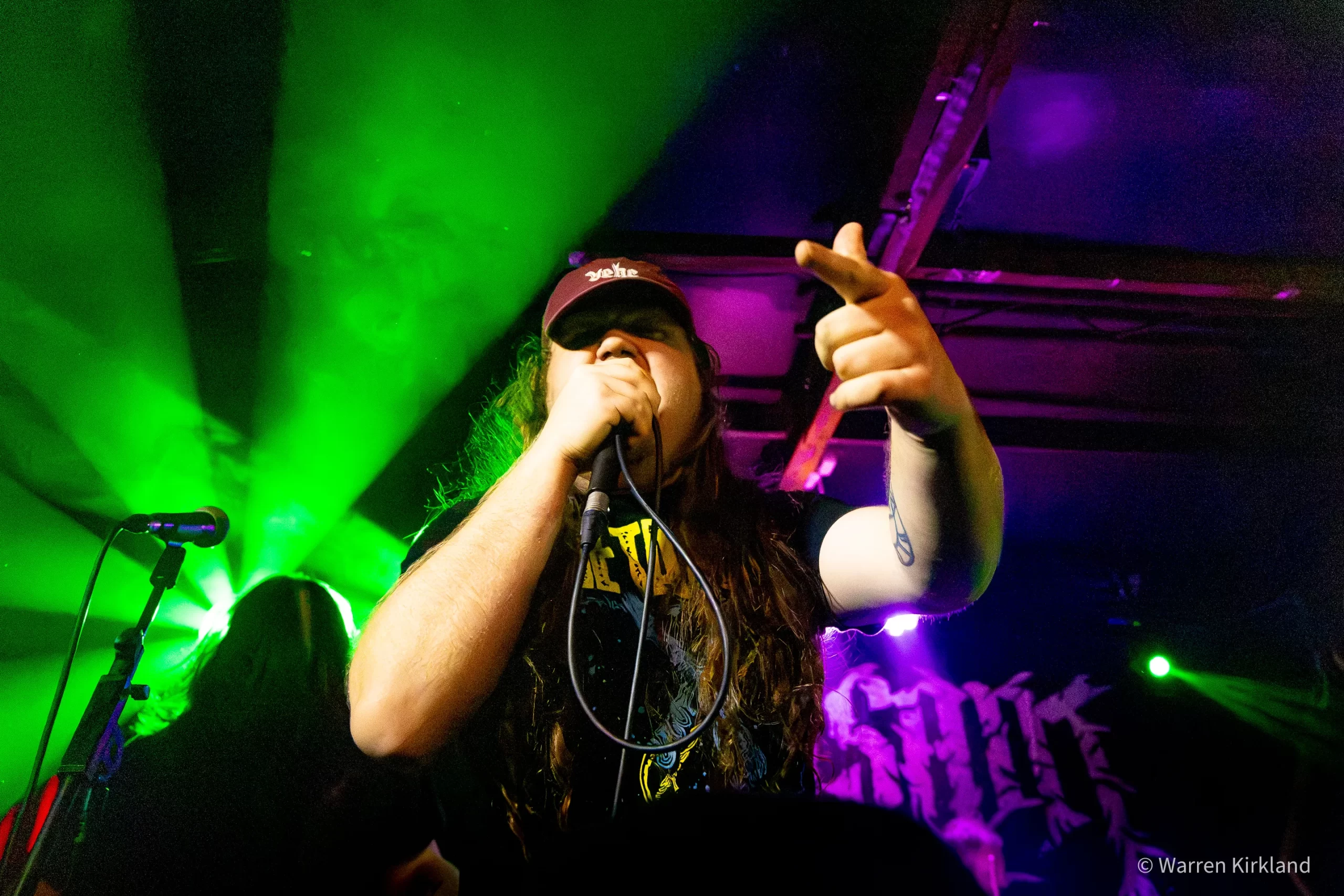 Peasant vocalist shouting into a microphone under green stage lighting