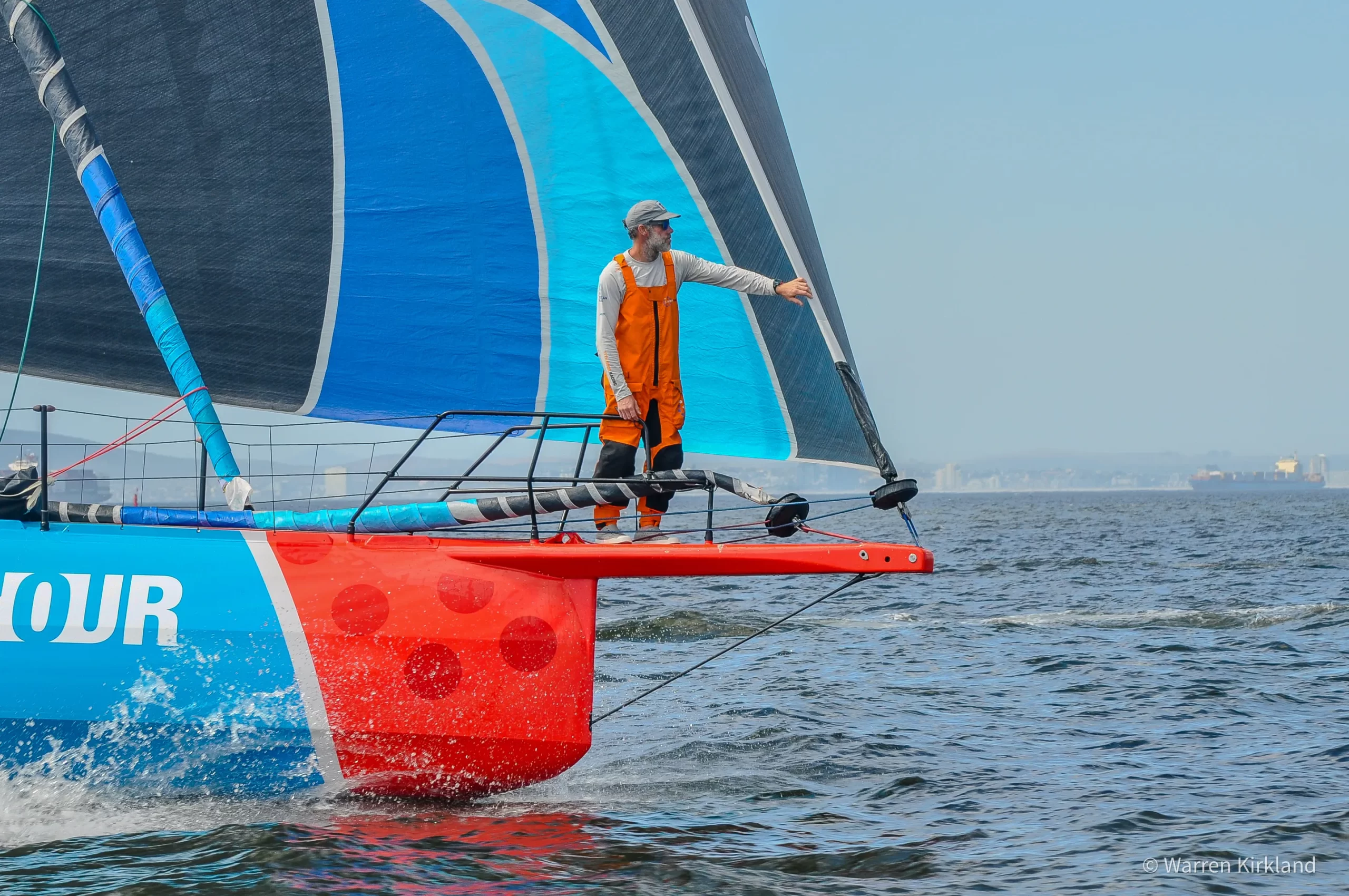 Sailor standing on the bowsprit of an ocean racing yacht, The Ocean Race
