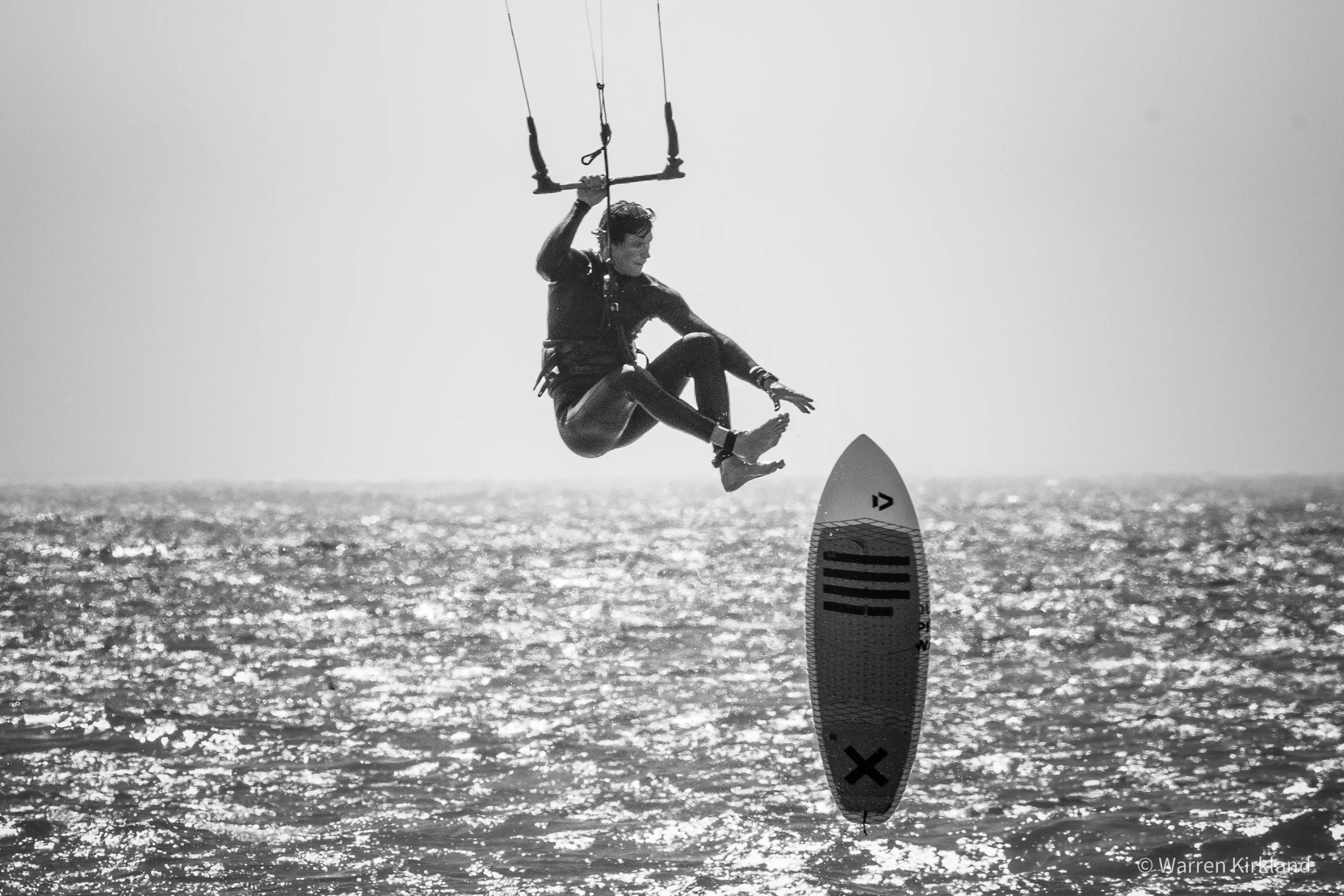Kitesurfer catching air over the water, black and white, Misty Cliffs, Cape Town