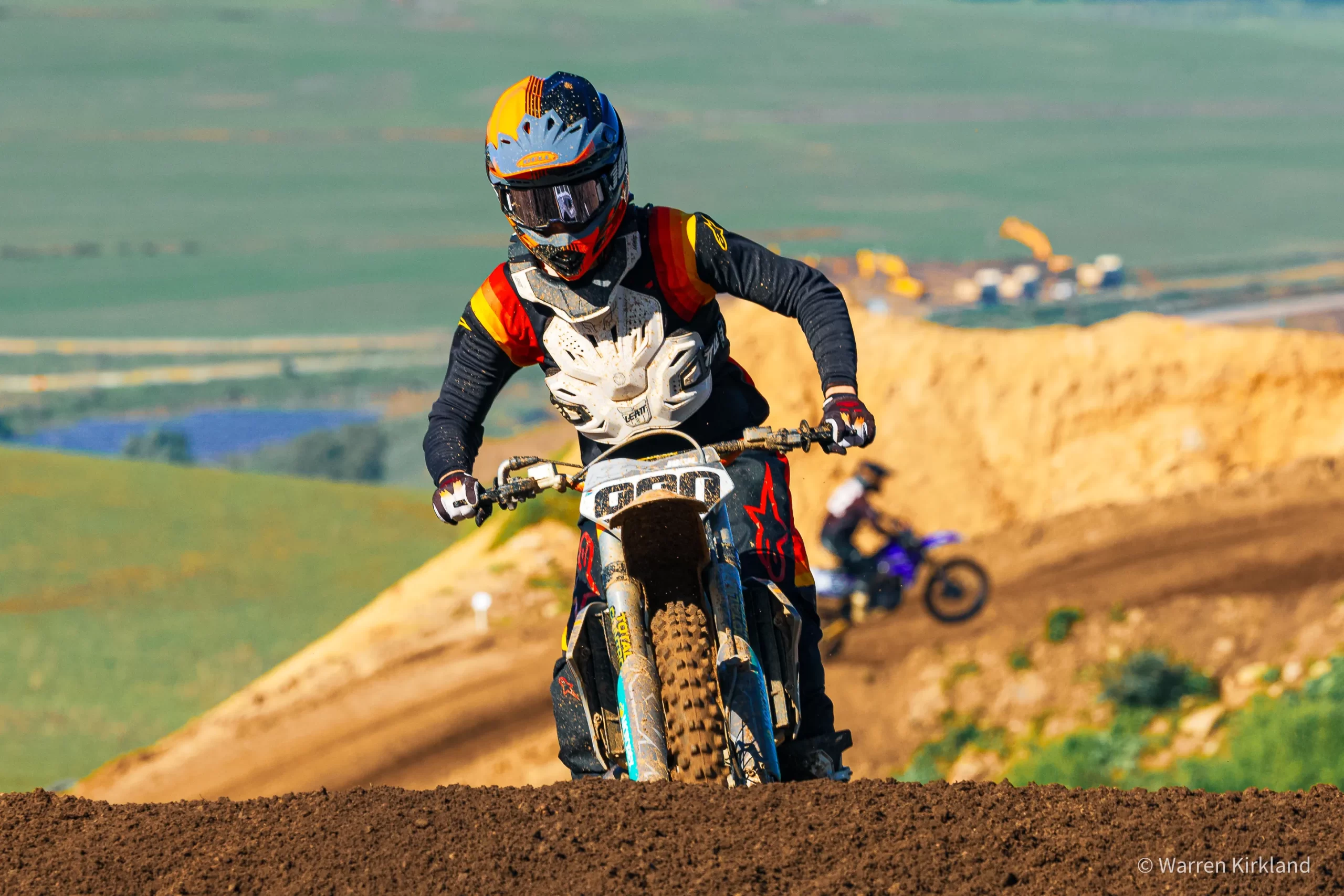 Motocross rider standing on the pegs riding along a hilltop track