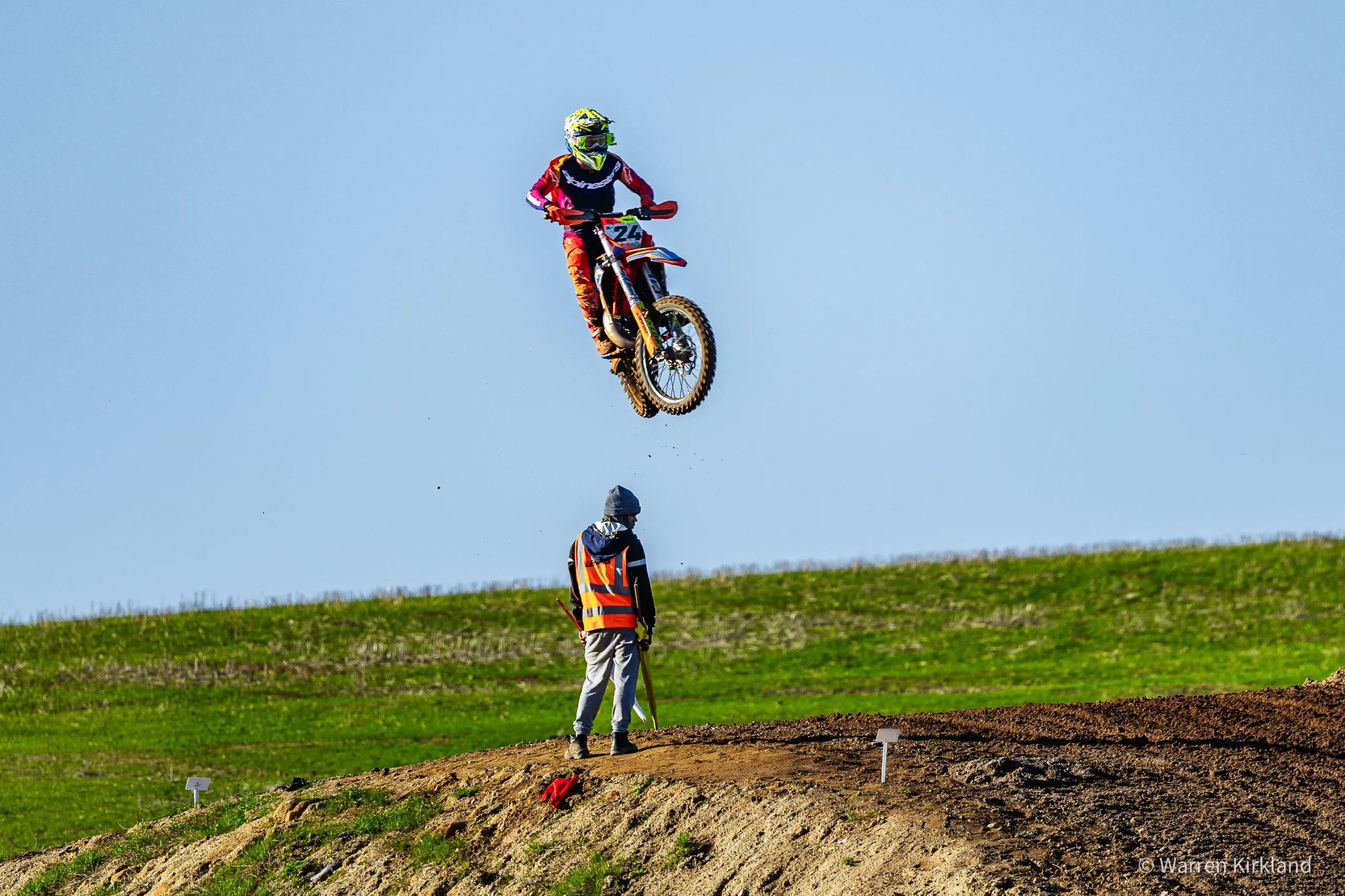 Motocross rider mid-jump watched by a track marshal, SA National Motocross