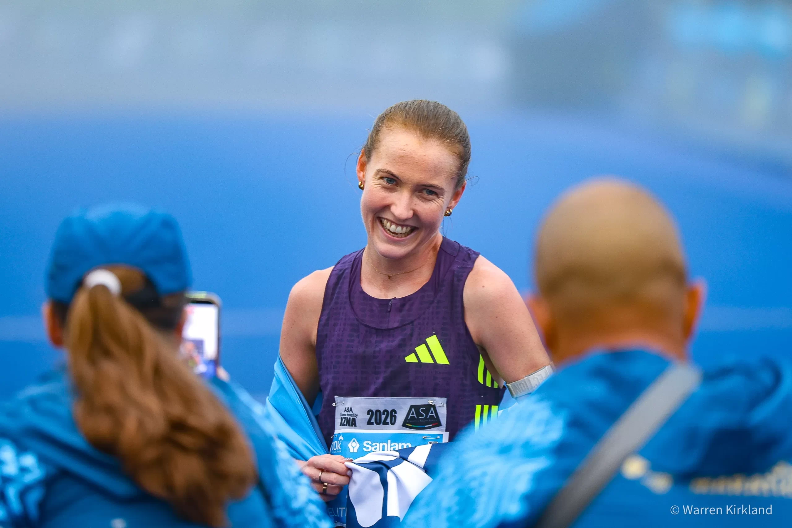 Runner smiling for a photo with a finisher's towel, Cape Town Marathon