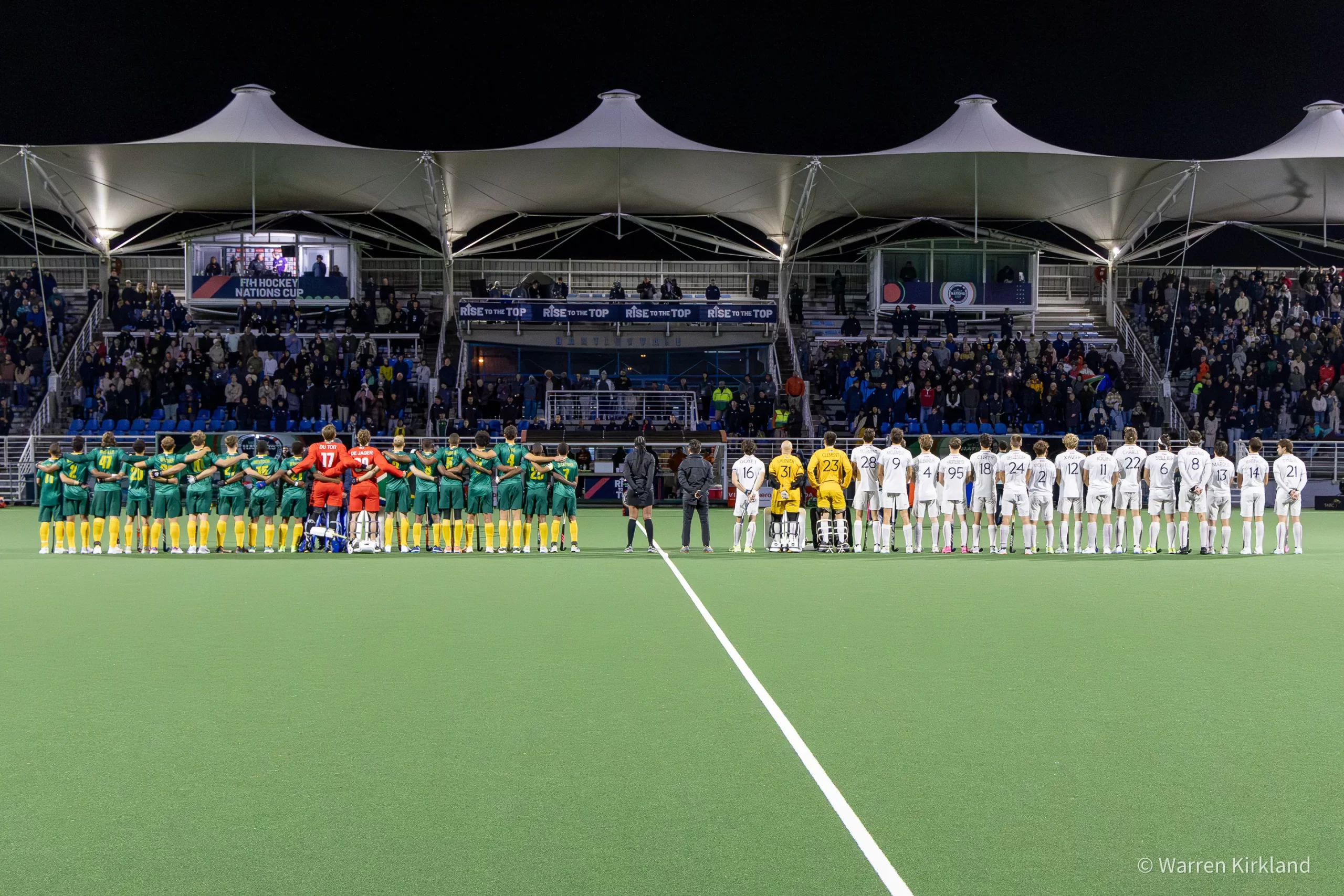 Both teams lined up on the pitch before kick-off, floodlit stadium, FIH Hockey Men's Nations Cup