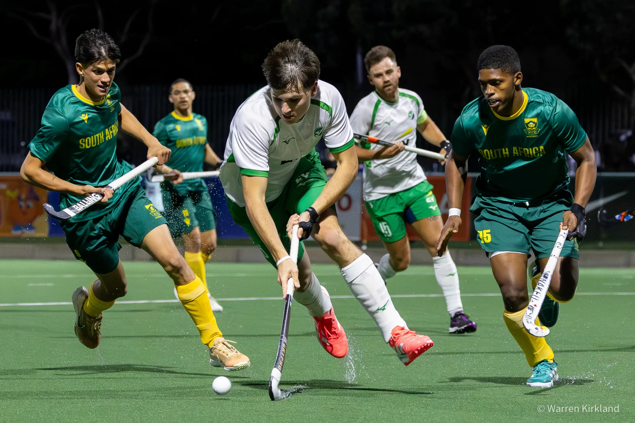 South Africa hockey players sprinting downfield, water spray from the pitch, FIH Hockey Men's Nations Cup