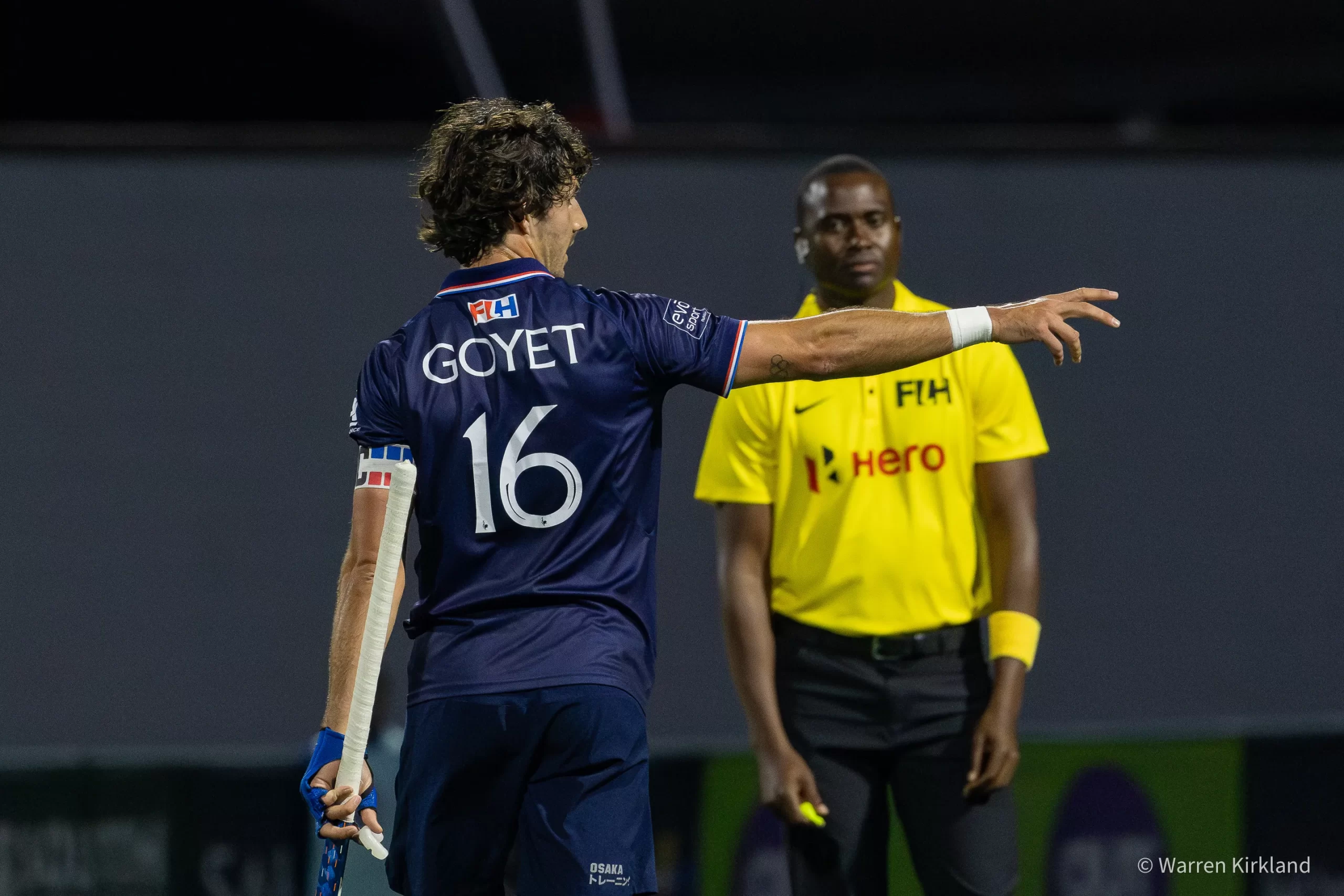 Hockey player gesturing toward the umpire during a night match, FIH Hockey Men's Nations Cup