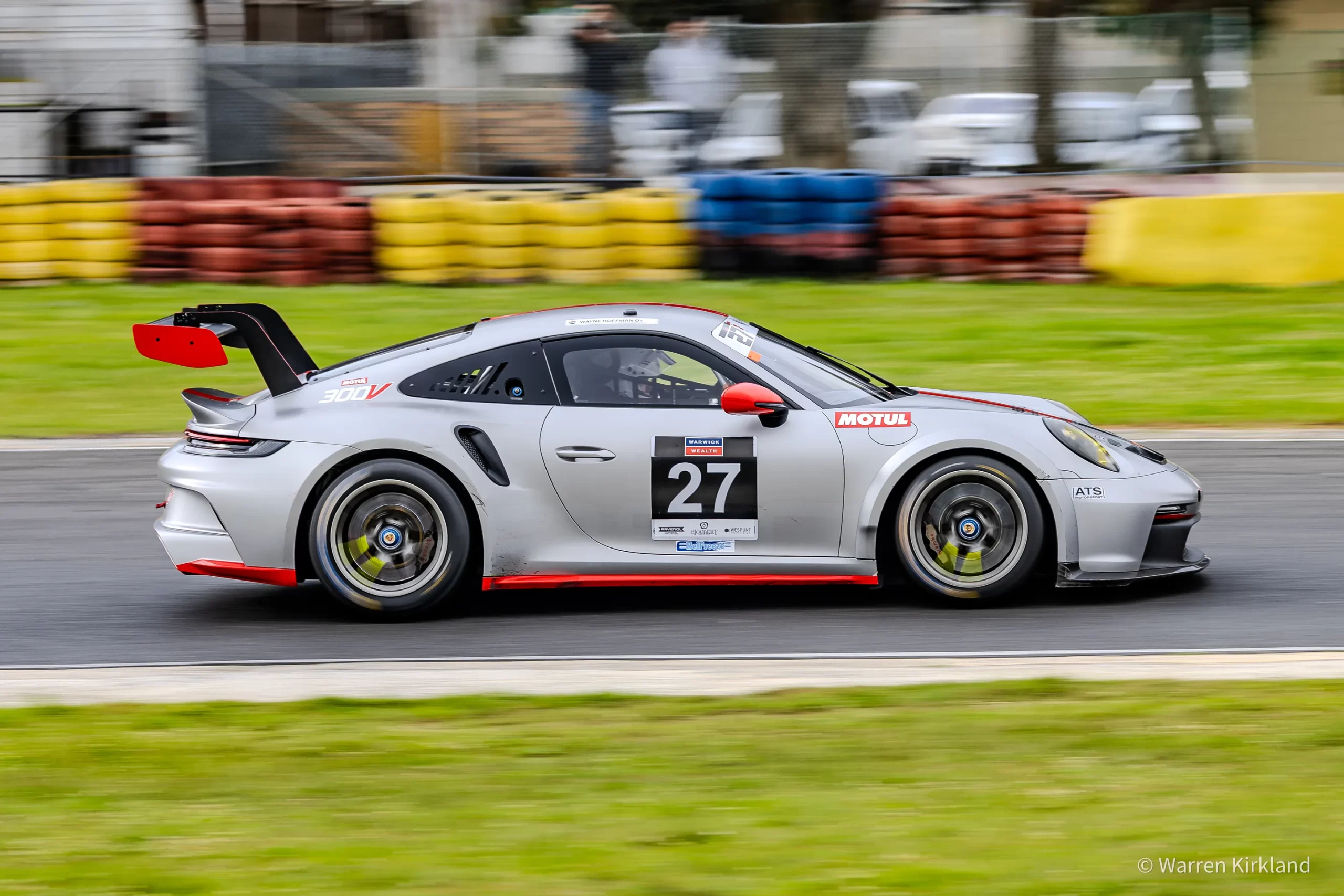 Silver Porsche GT3 race car cornering, side profile